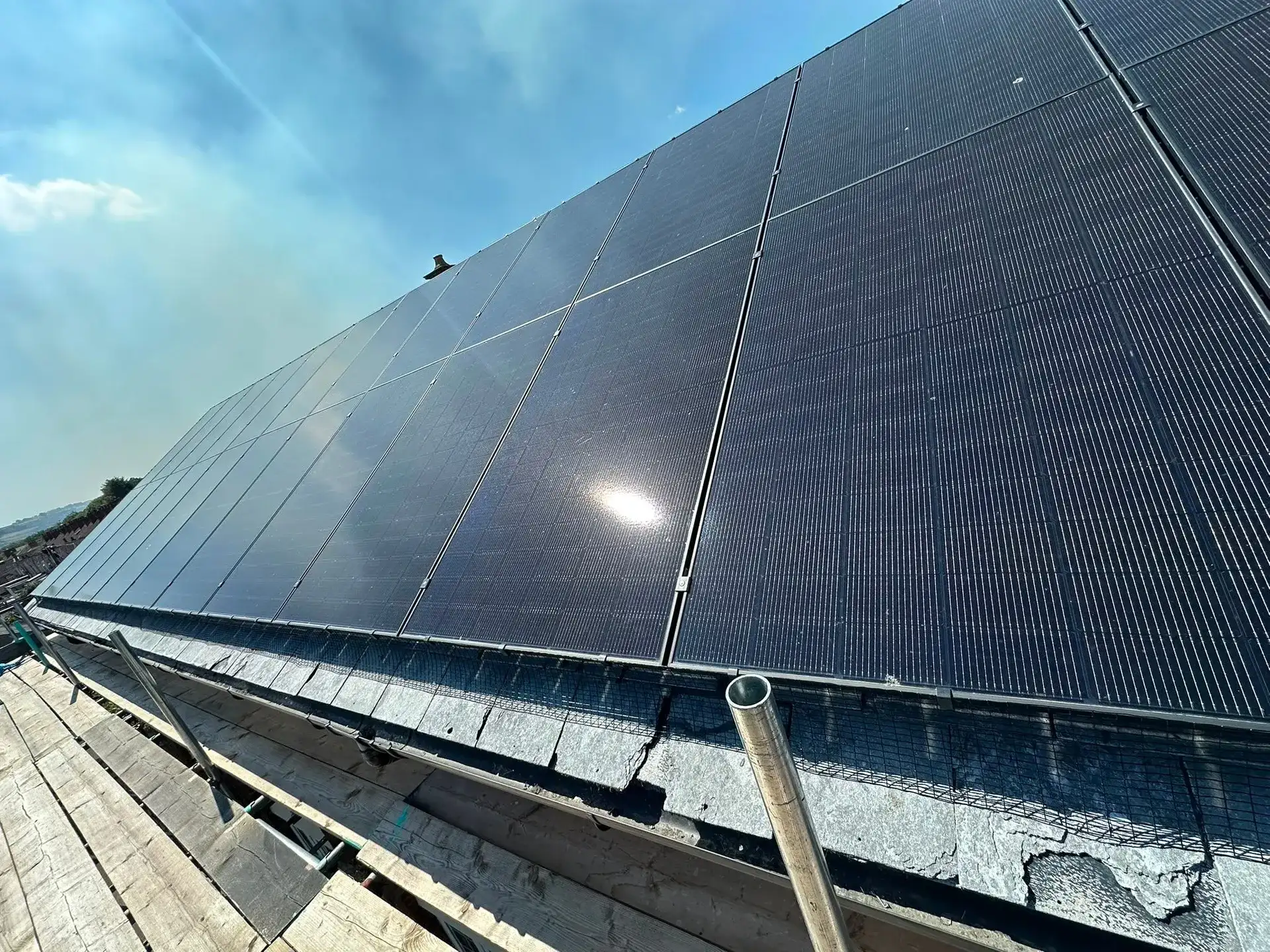 Dark solar panels covering a pitched roof in bright daylight