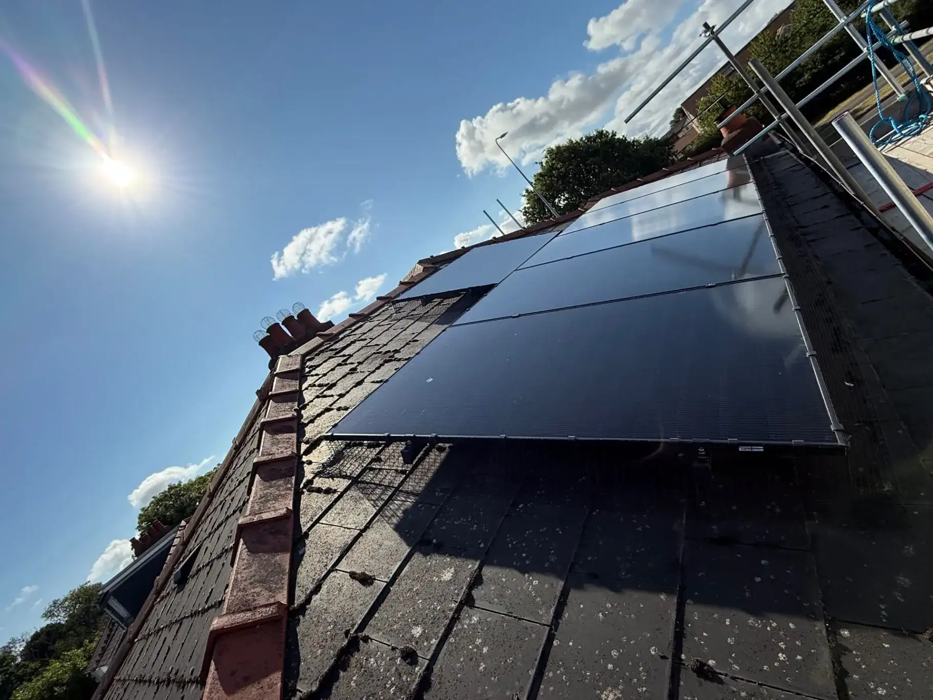 Dark solar panels installed on a pitched roof under a blue sky